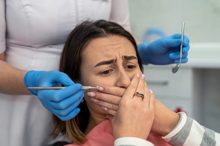 Young female patient covering her mouth with hands at the dentist's appointment. Concept of no pain. Dental procedure