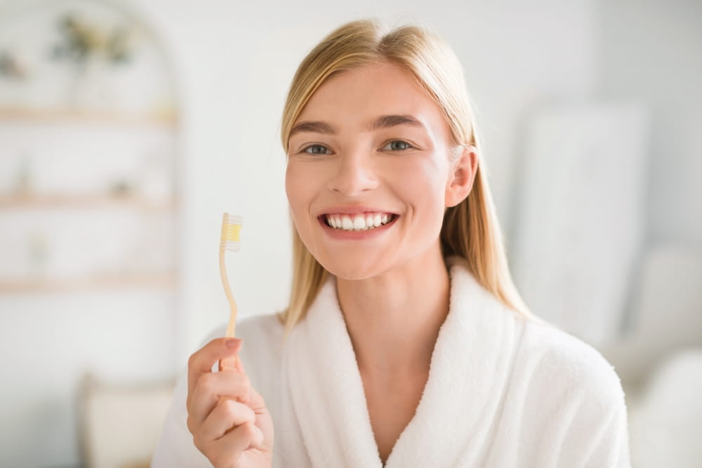 Perfect Smile. Happy Young Blonde Woman Posing With Toothbrush Brushing Teeth Looking At Camera In Modern Bathroom
