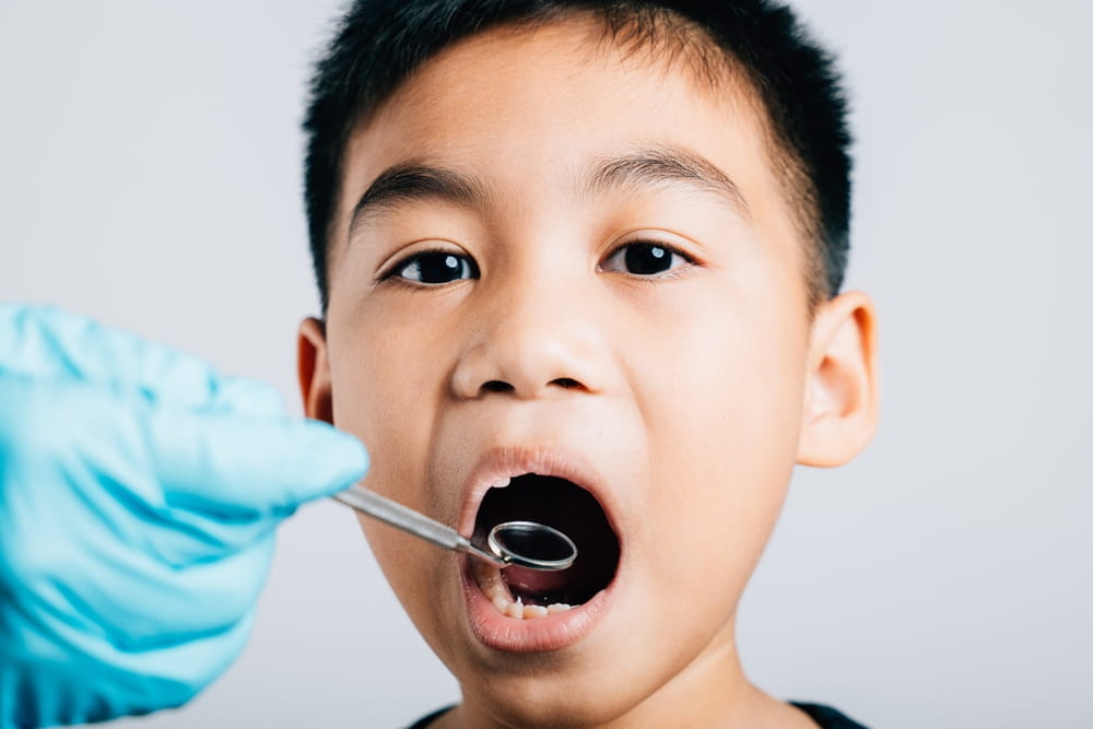 A pediatric dentist examines a child's mouth after extracting a loose milk tooth
