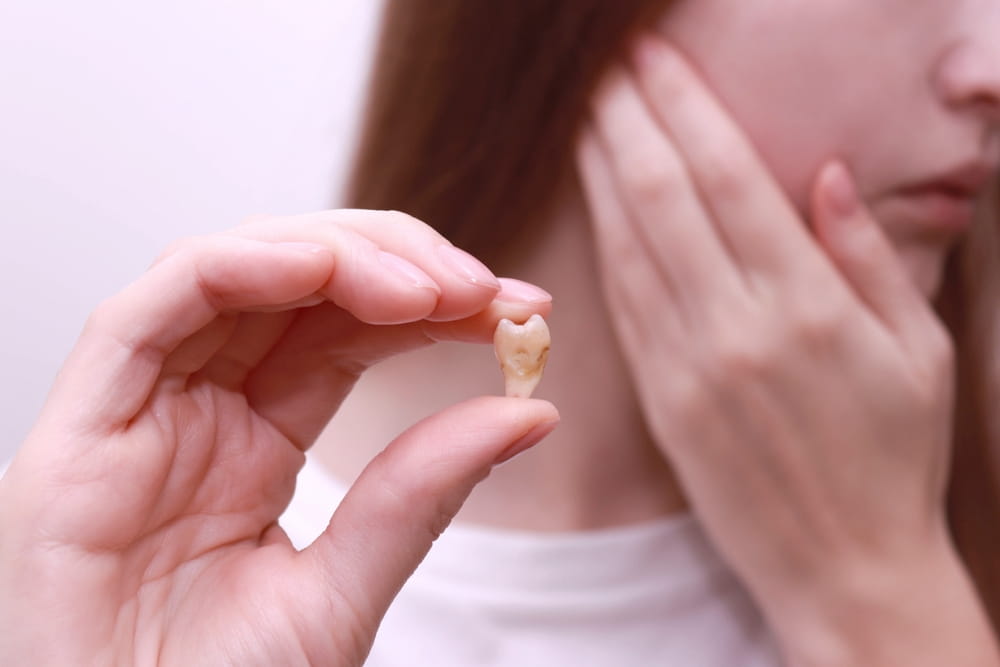 Woman holding wisdom tooth after extracted of a tooth.